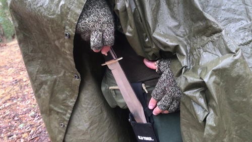 Putting Bowie in sheath on wet day under poncho.
